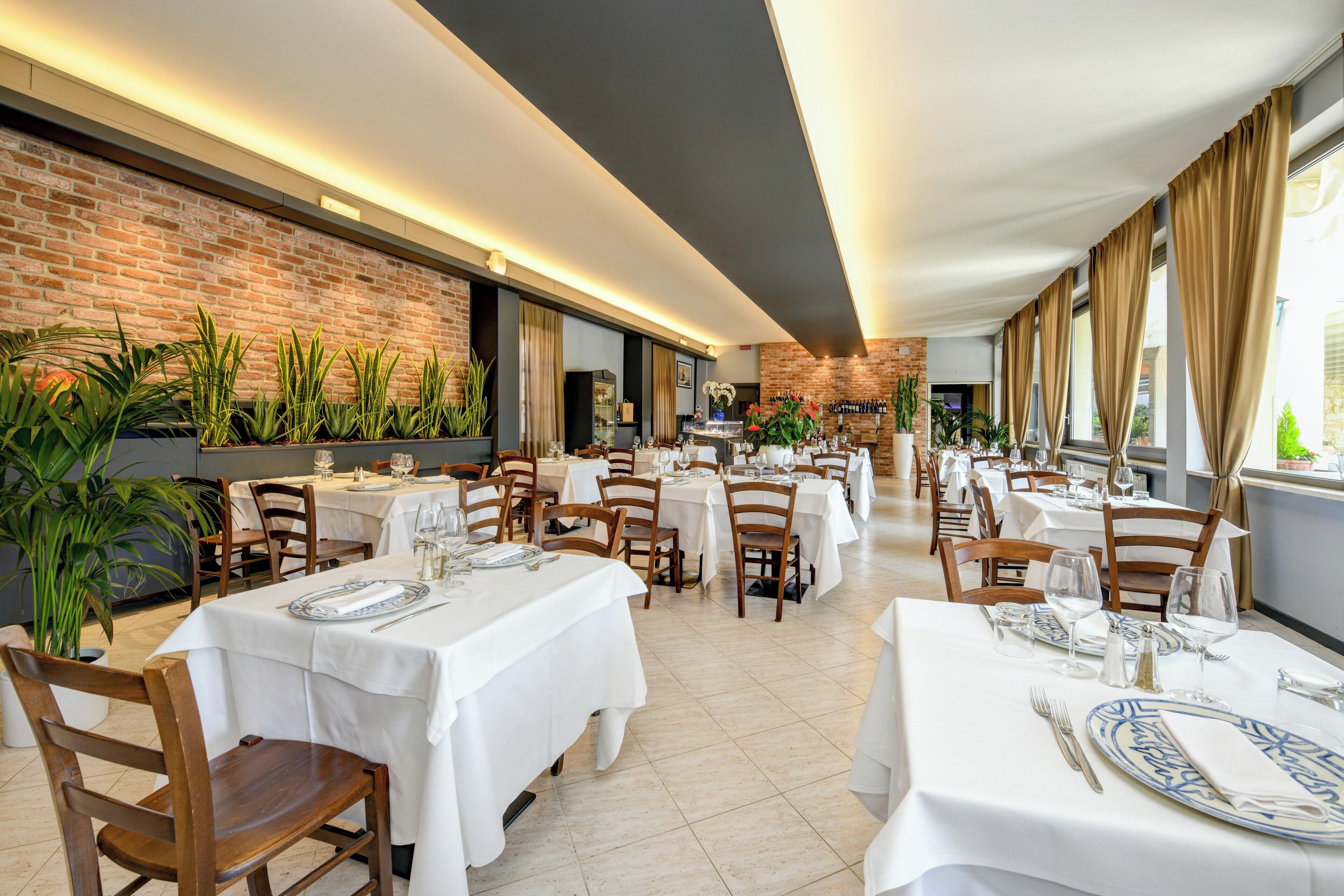 Un restaurant aux murs de briques, aux nappes blanches et aux chaises en bois.