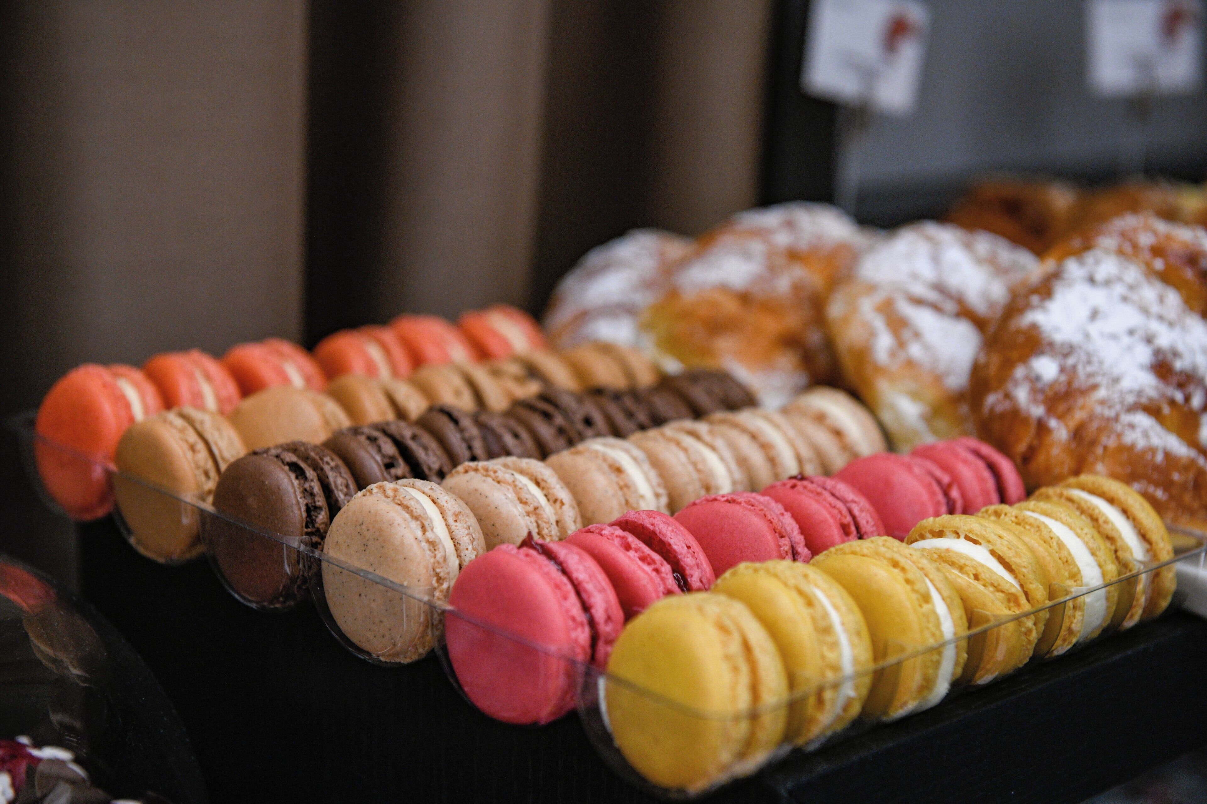 Una exhibición de pasteles variados, incluyendo macarons y donas.