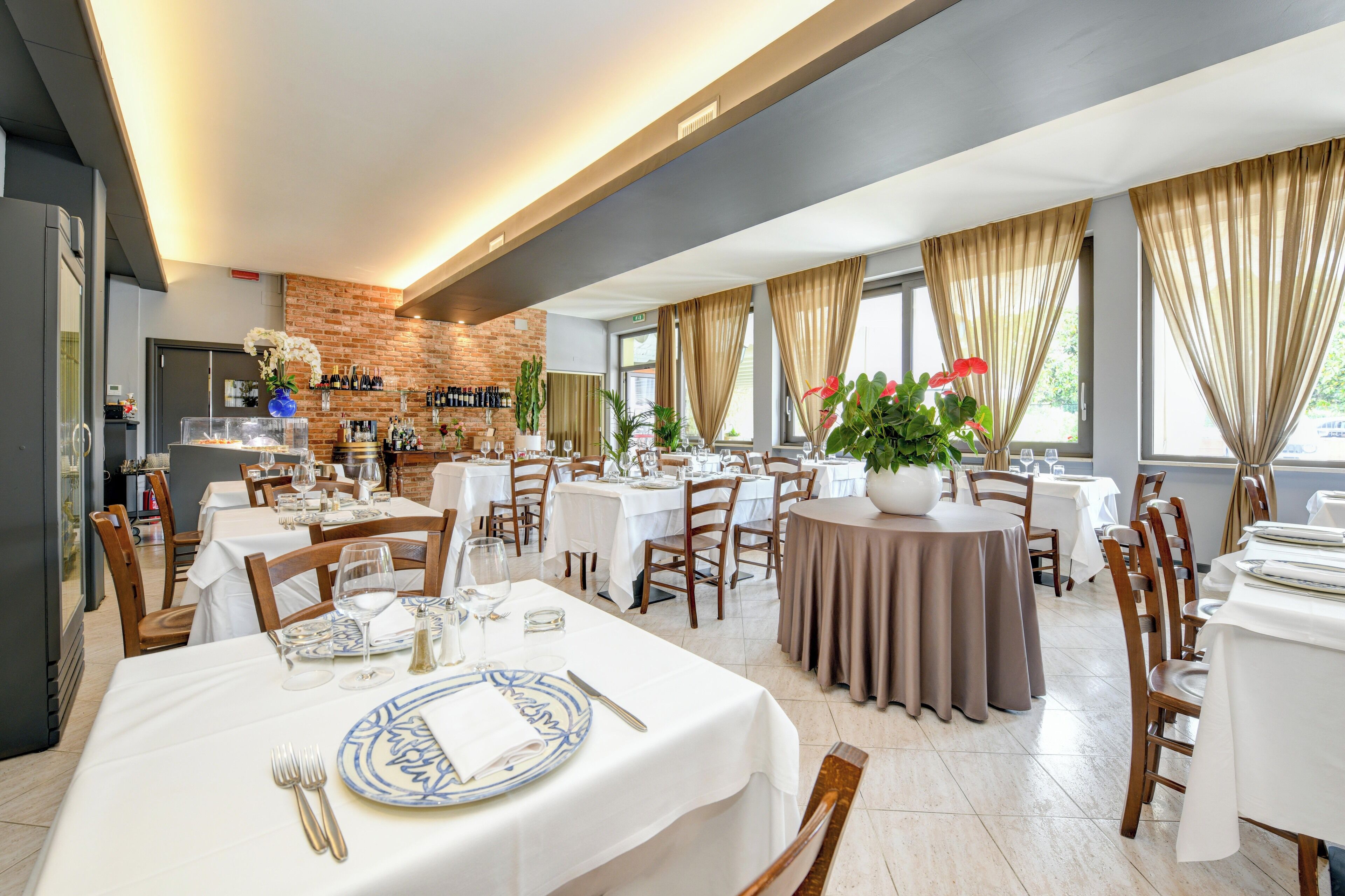 Un restaurante con varias mesas, sillas y una pared de ladrillo.