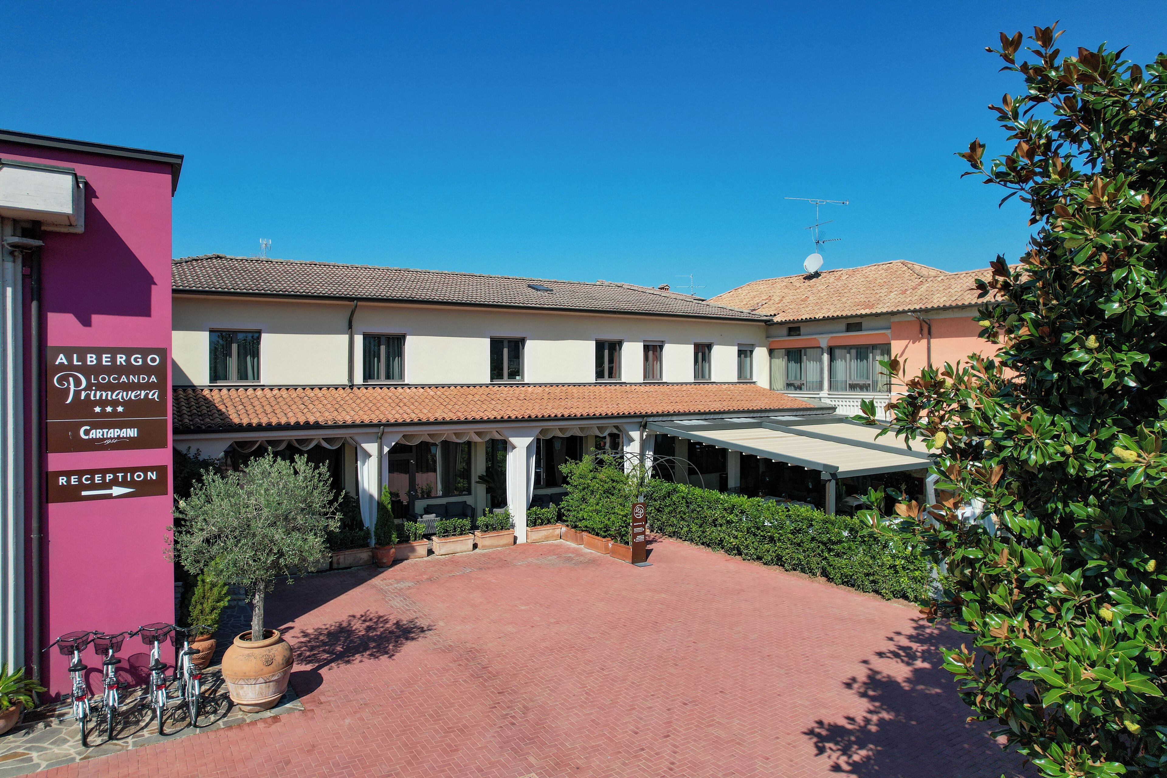 Un edificio con un letrero que dice 'Albergo Locanda Cartapani' y una zona de recepción.