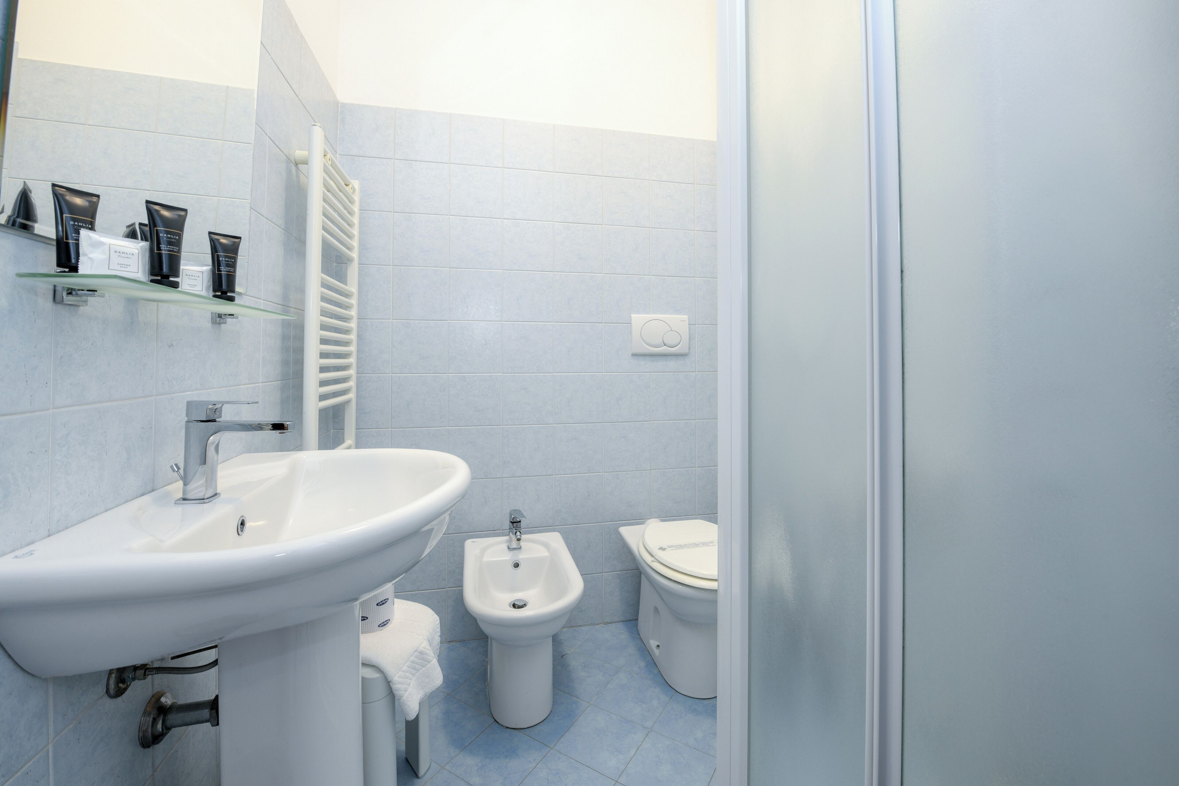 A modern bathroom with a white sink, bidet, and toilet.