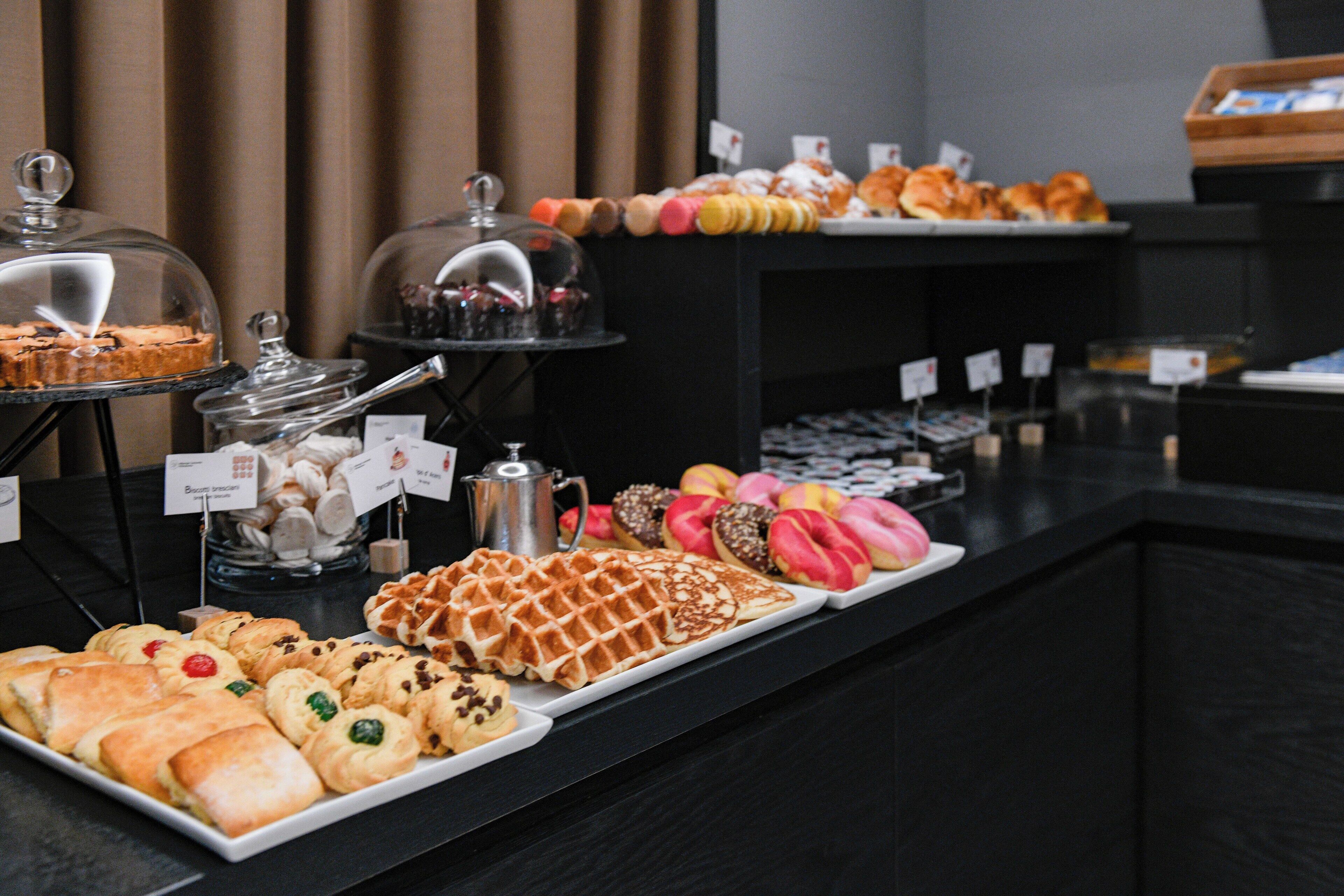 A buffet with various pastries and desserts, including waffles, croissants, and macarons.