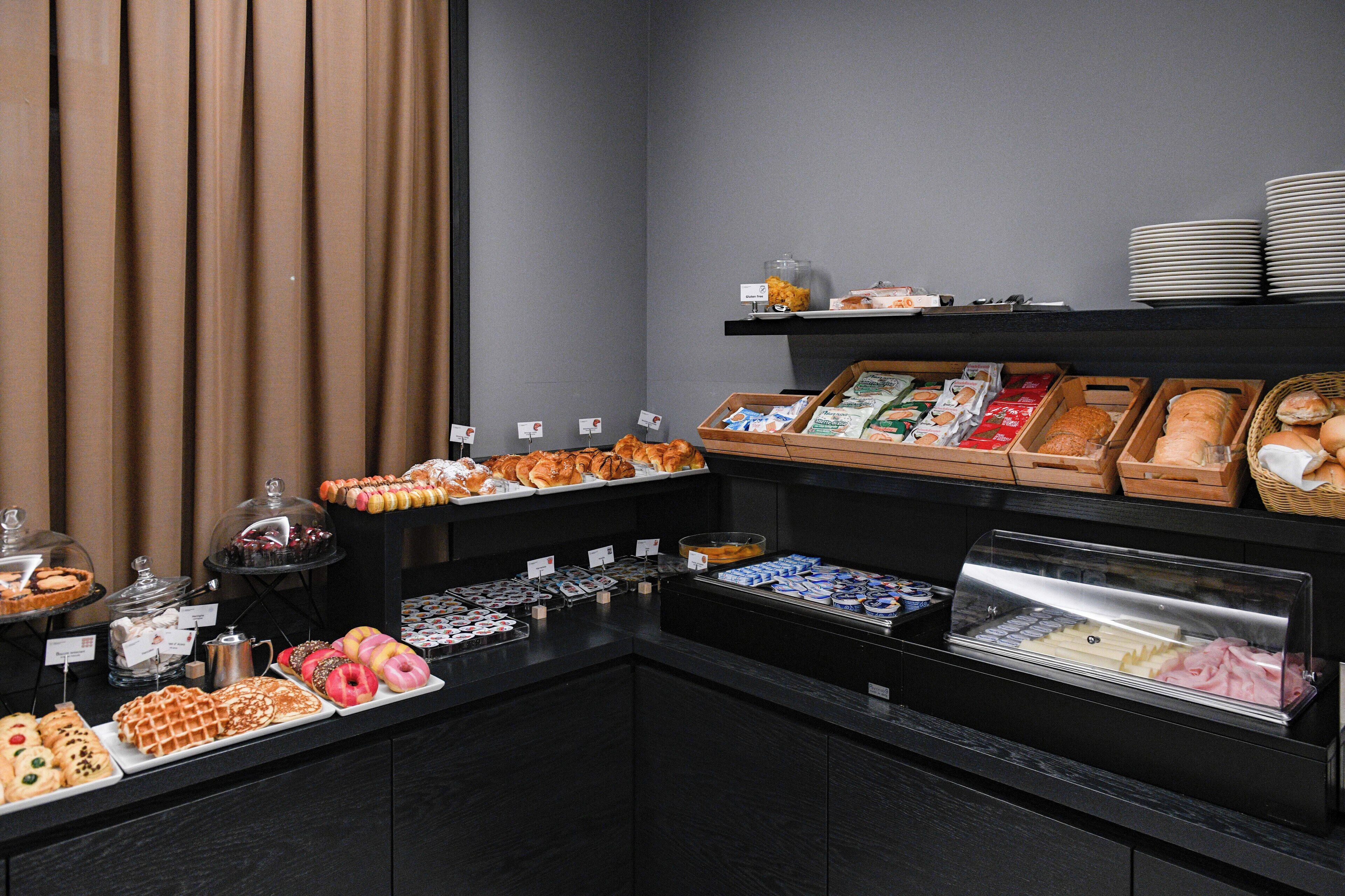 A buffet with various food items including pastries, breads, and desserts.