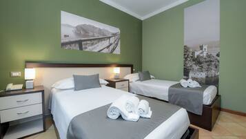 A hotel room with two beds, a nightstand with a phone, and a large painting of a bridge.