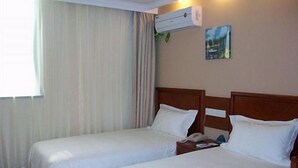 A hotel room with two single beds, a window with curtains, an air conditioning unit, and a small painting on the wall. - Greentree Inn Shanghai Zhangjiang (Shanghai)