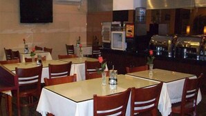 A restaurant with tables covered in white tablecloths, wooden chairs, and a television mounted on the wall. - Greentree Inn Shanghai Zhangjiang (Shanghai)