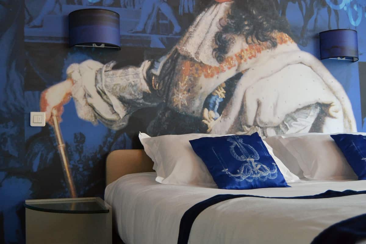 A bedroom with a bed, pillows, a nightstand, and a wall mural.