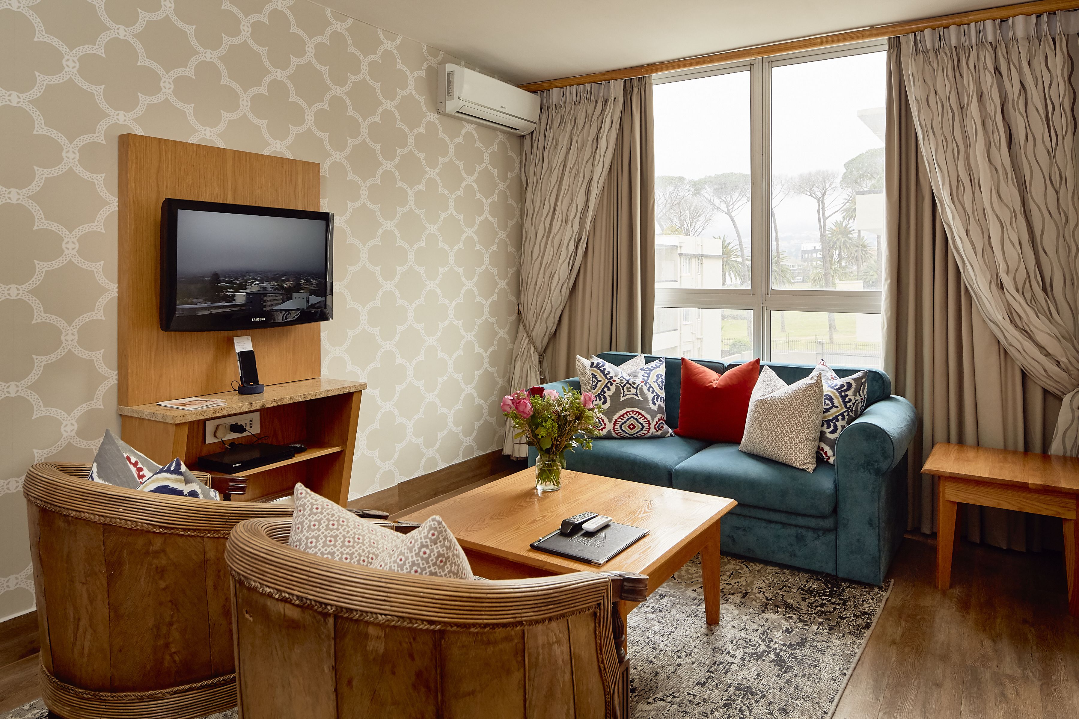 A living room with a television, sofa, and two wicker chairs.