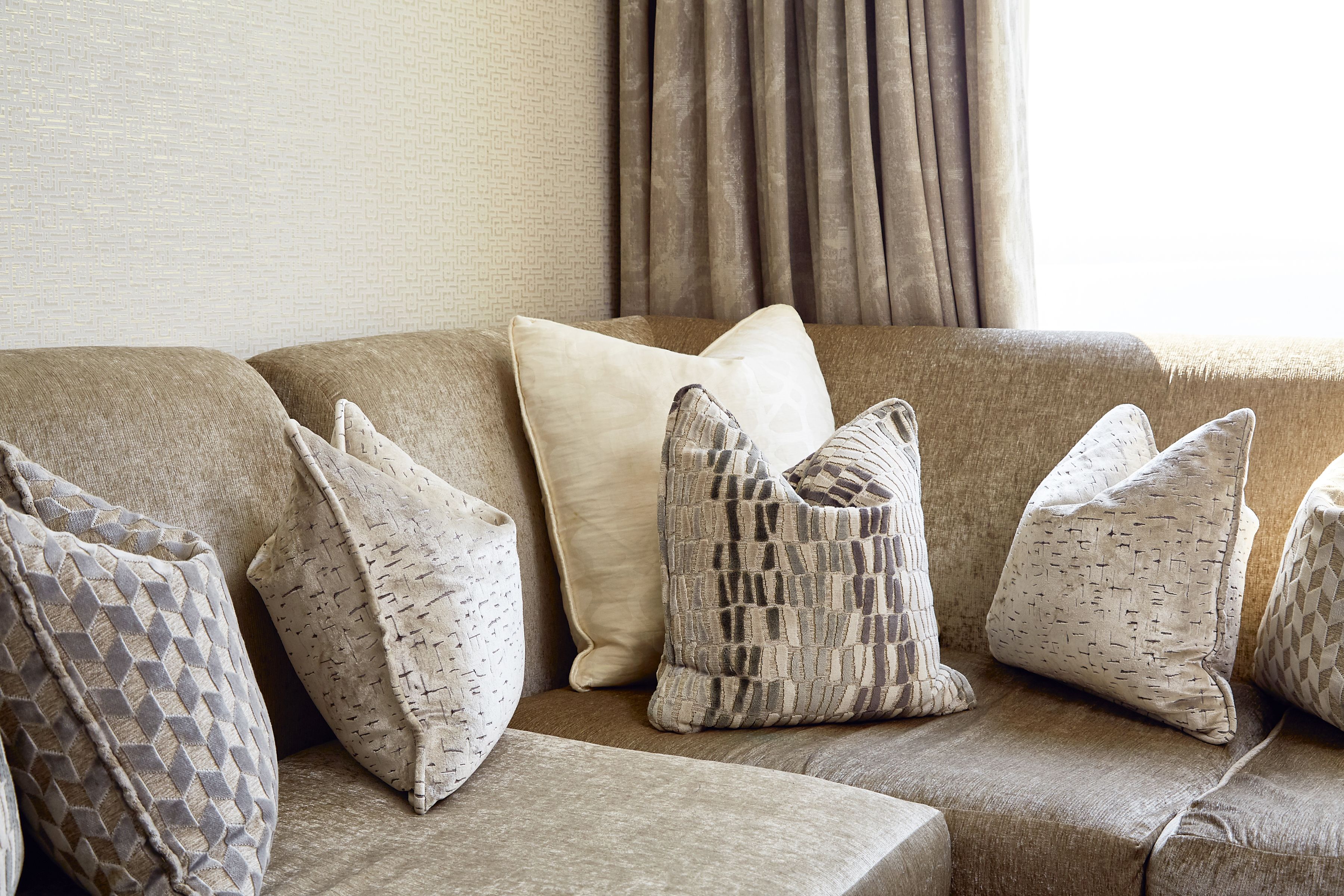 A beige sofa with multiple patterned cushions.