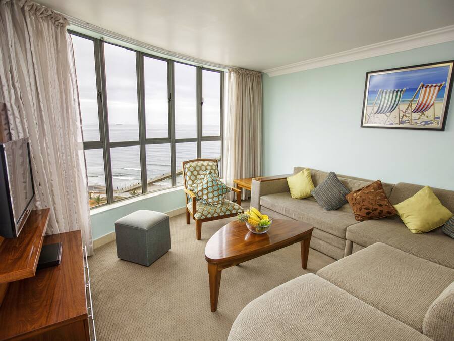 A living room with a large window, a sofa, a coffee table, a TV, and a chair.