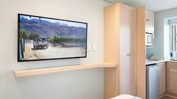A modern kitchen with a built-in dishwasher, wooden cabinets, and a flat-screen TV mounted on the wall.