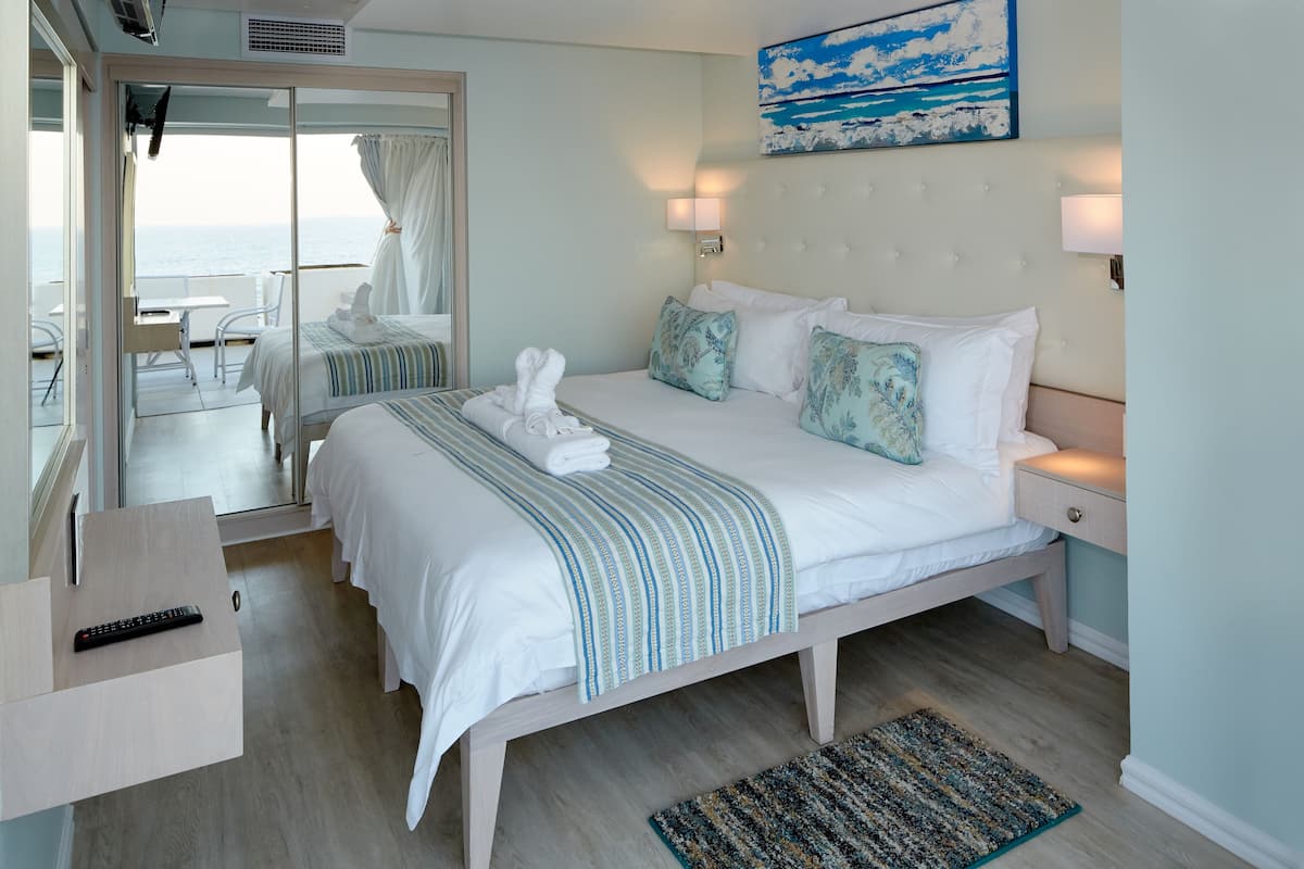 Una habitación de hotel con cama, mesita de noche y vista al mar.