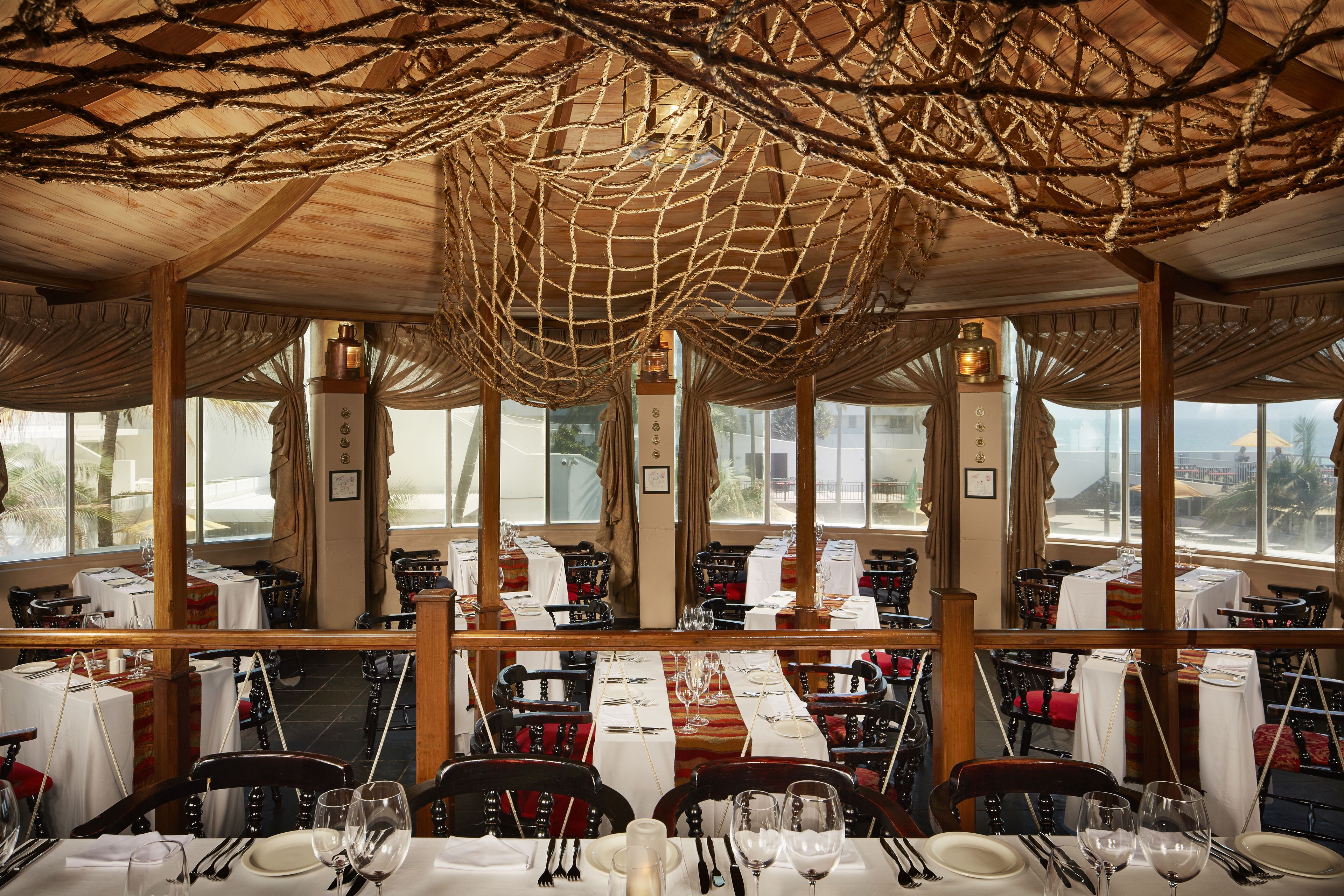 Un ristorante con diversi tavoli, sedie e una grande struttura a volta in rete.