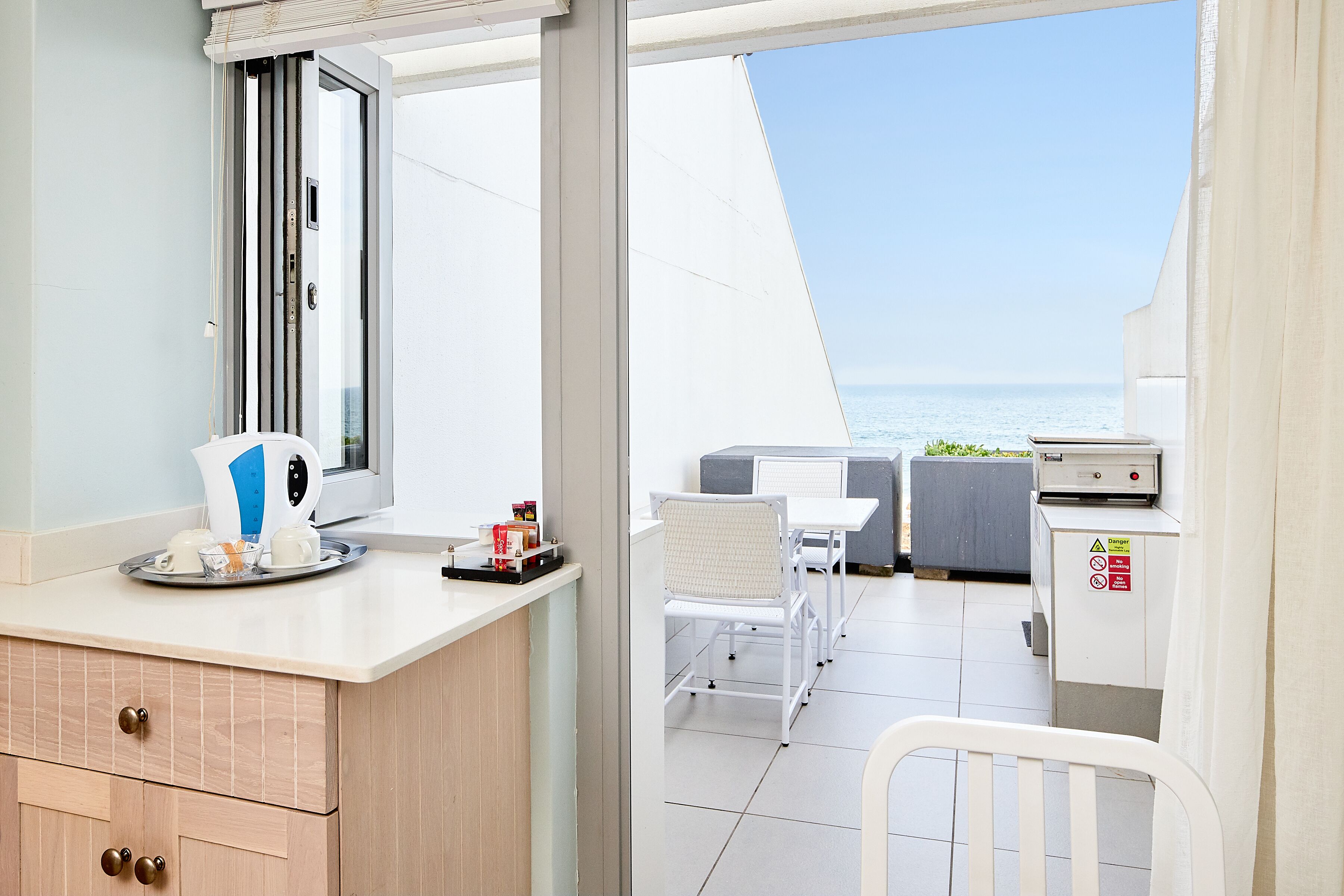 A kitchen area with a coffee maker, a tray with cups, and a small refrigerator.