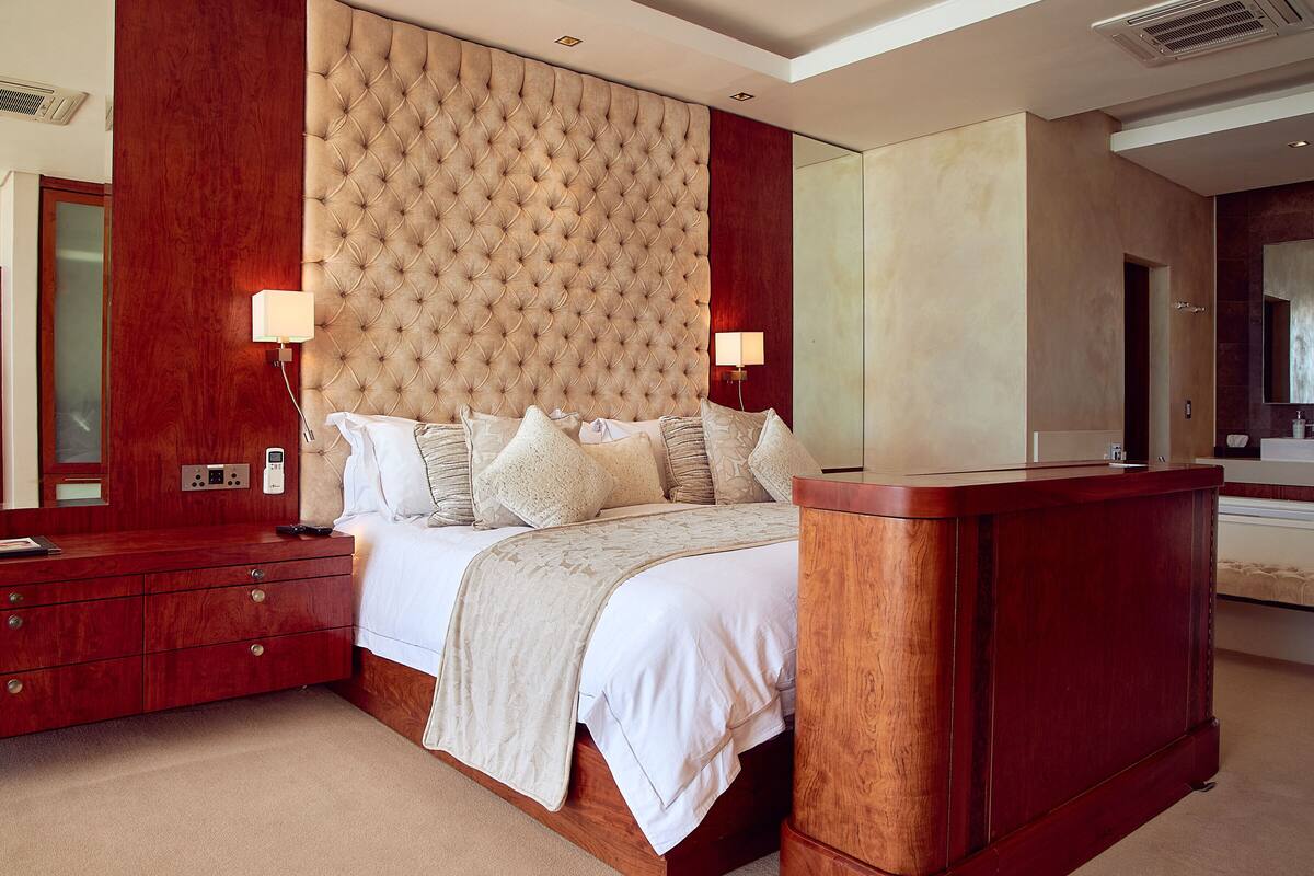 Un dormitorio con una cama grande, cabecera de madera, mesitas de noche y una mesilla.