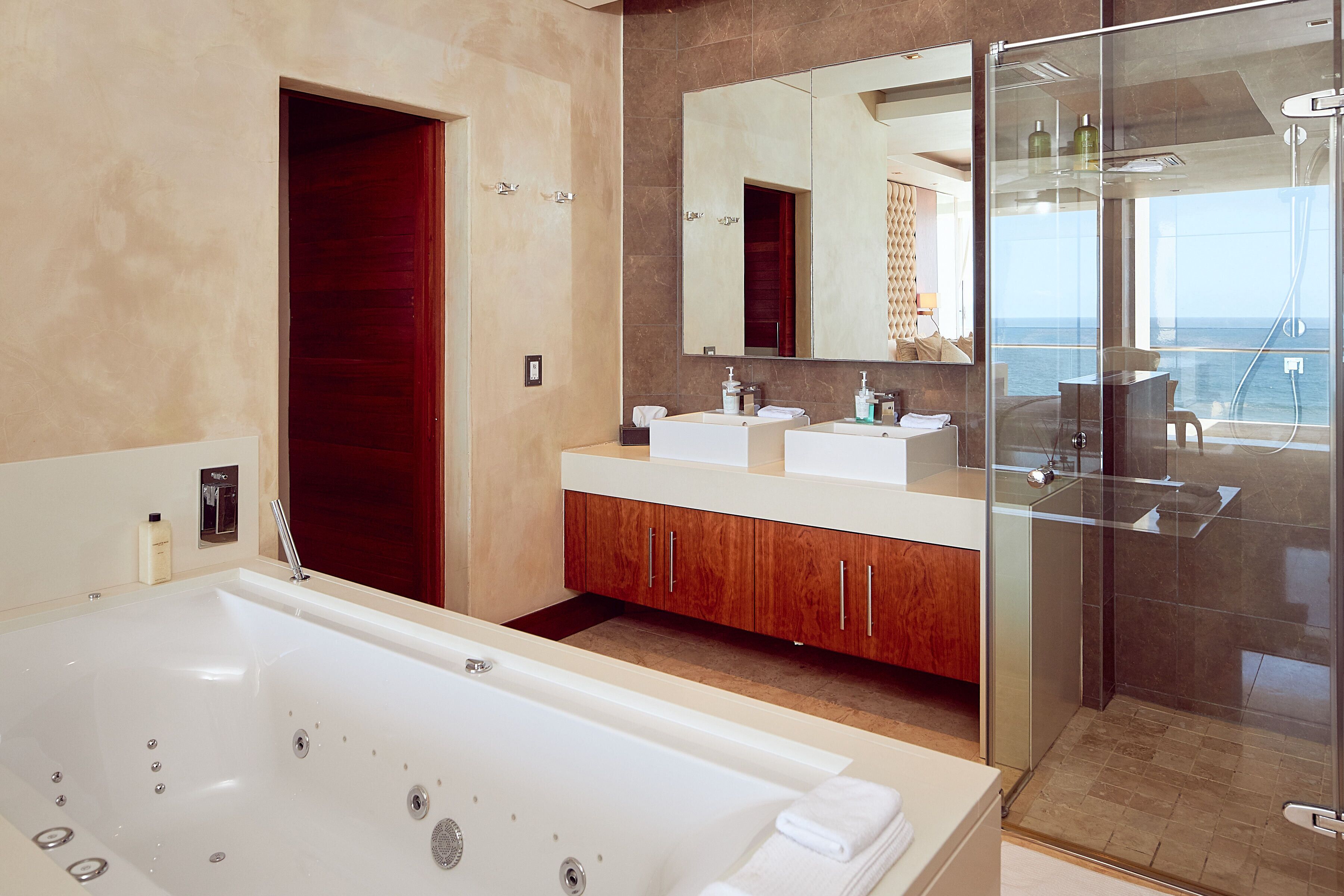 A modern bathroom with a large bathtub, dual sinks, and a glass-enclosed shower.