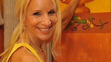 A person holding a paintbrush, painting a vibrant floral design on a wall.