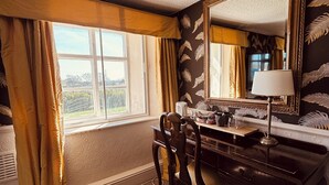 A room with a large window, a desk with a lamp, and a mirror.