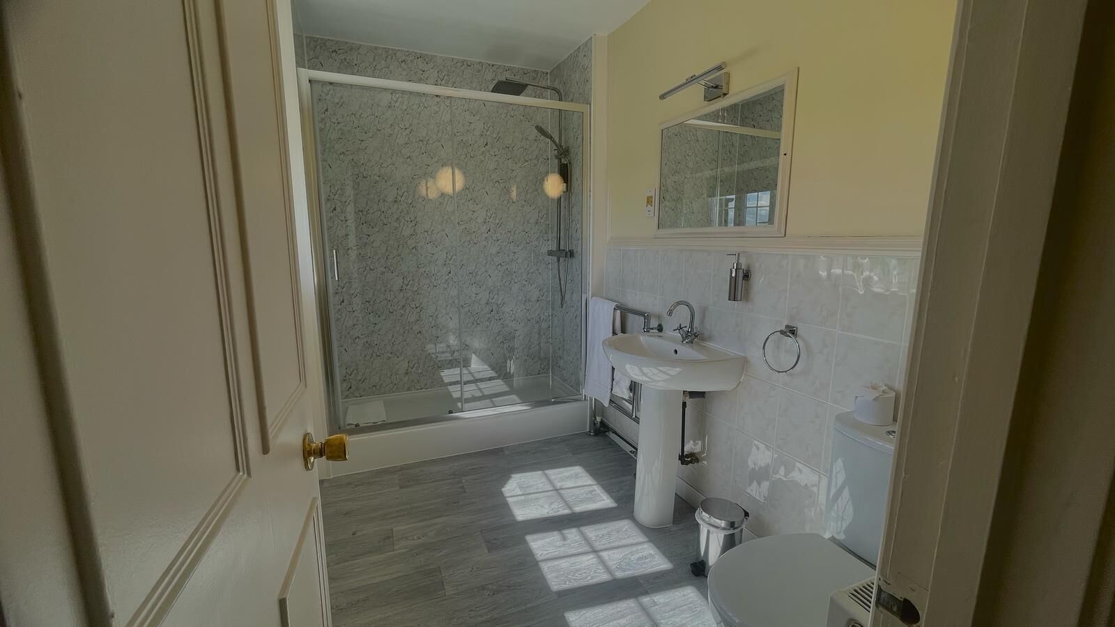 A bathroom with a glass shower, a sink, and a toilet.