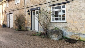 A stone building with a gravel driveway, a white door, and a window with a white frame.