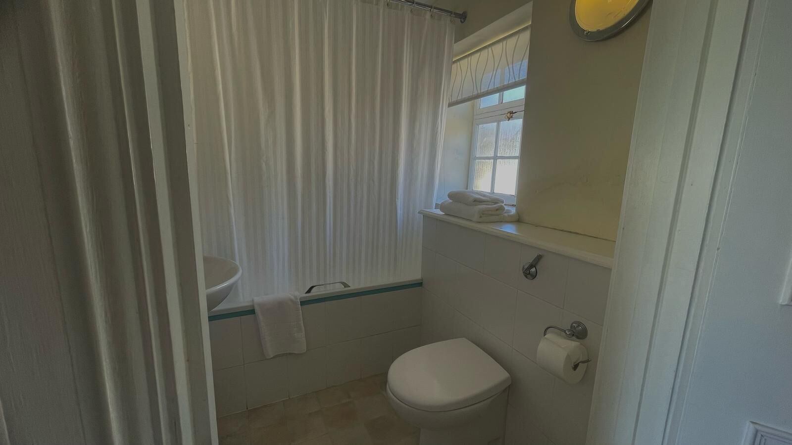Un baño pequeño con inodoro, lavamanos y ventana.