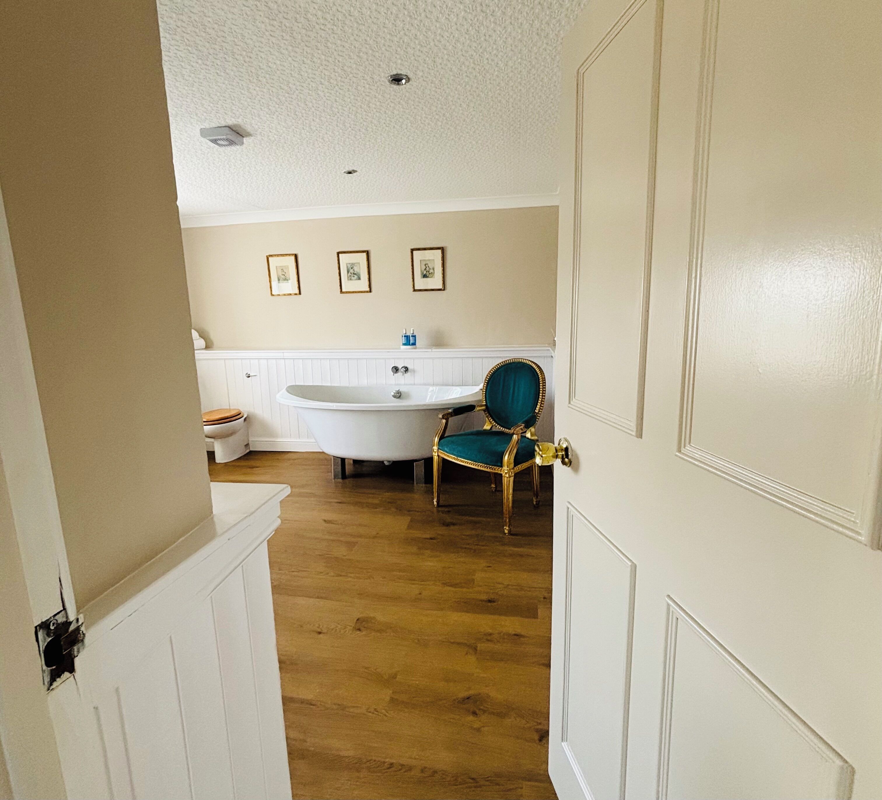 Een badkamer met een bad, een toilet en een stoel.
