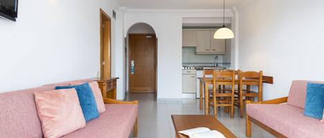 Una sala de estar moderna con un sofá, una mesa de madera y una cocina al fondo.