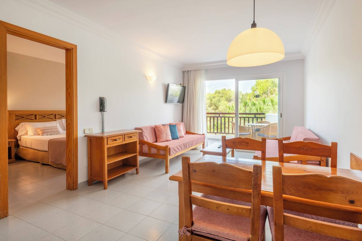 Un'ampia stanza con un letto, una poltrona, un tavolo da pranzo e un balcone con mobili da esterno.