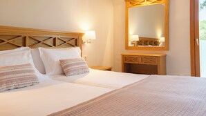 A double bed with two pillows, a bedside table, a mirror, and a wooden headboard. - Inturotel Esmeralda Garden (Santanyi)
