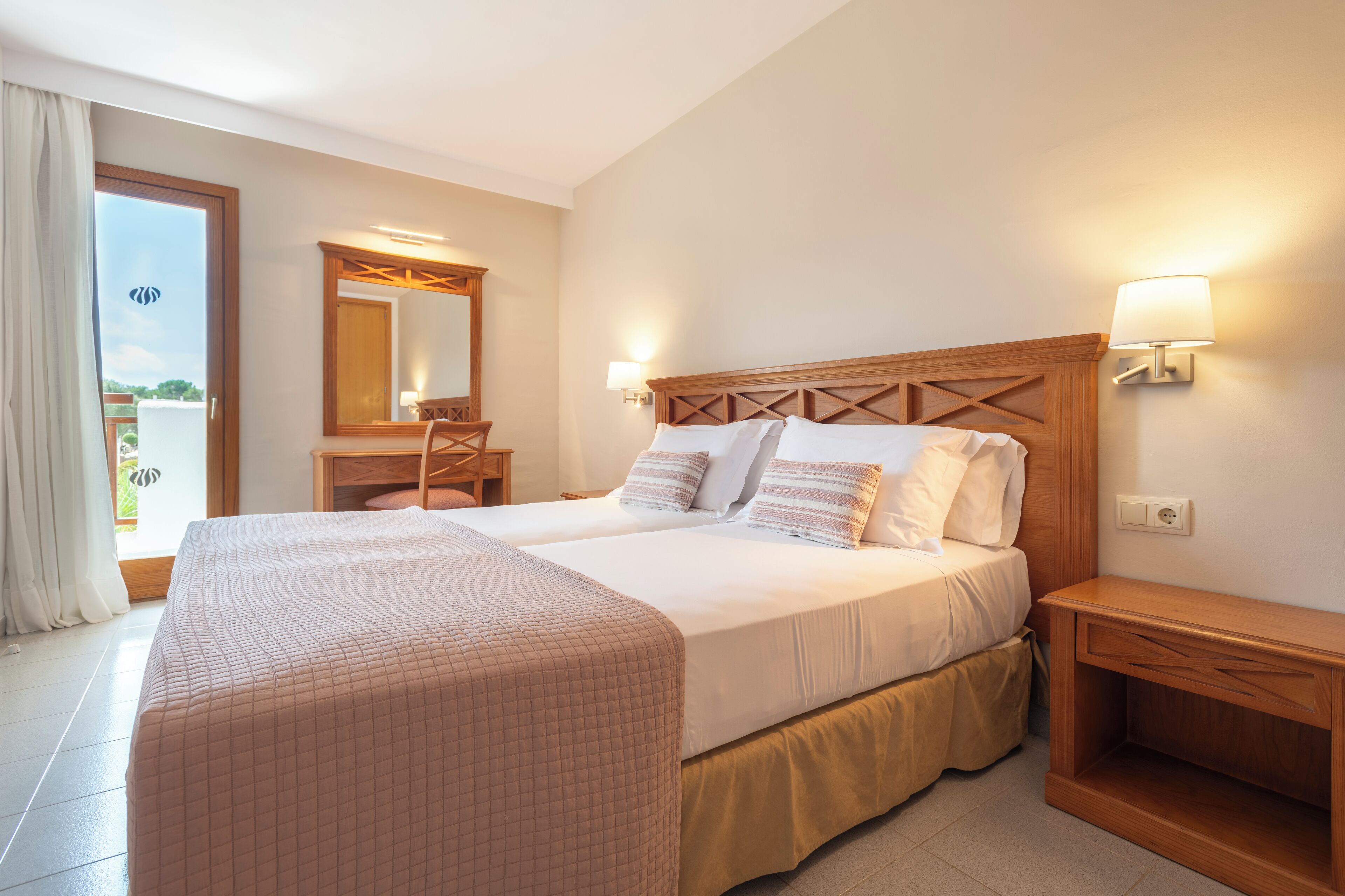 Habitación de hotel con una cama grande, un escritorio, una silla y un balcón con vistas.