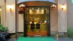 A hotel entrance with a glass door, a green carpet, and two lanterns on either side. - GreenTree Inn WenZhou XiaoNanMen Express Hotel (Wenzhou)