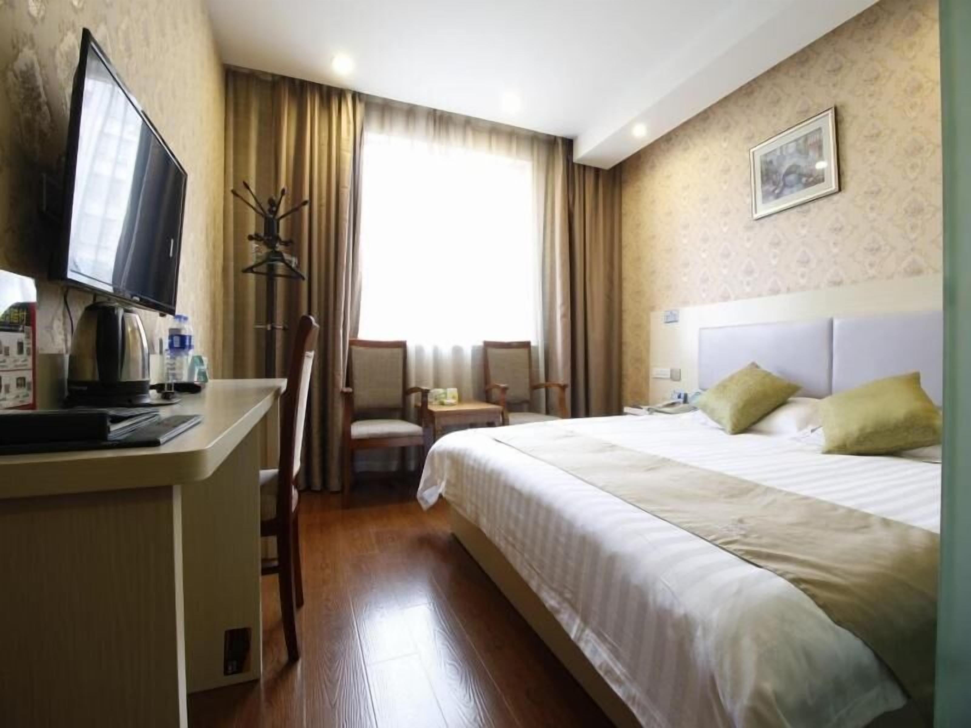Una camera d'albergo con un letto, una scrivania con un computer, una sedia e una televisione.