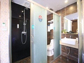 Une salle de bain moderne avec une douche à parois de verre, des toilettes et un lavabo surmonté d’un miroir.