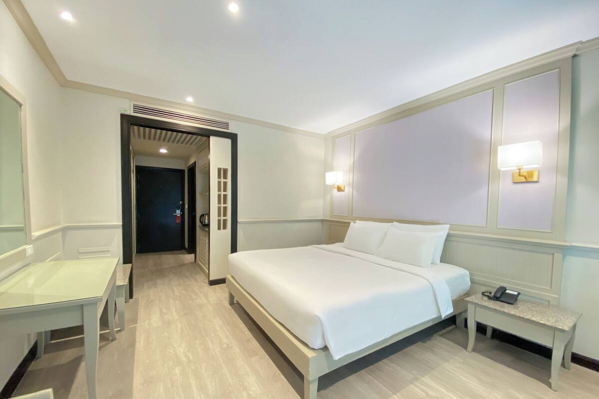 A hotel room with a bed, bedside table, desk, and chair.