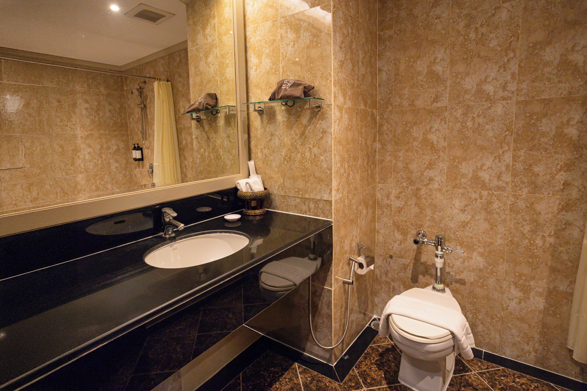 A modern bathroom with a black sink, a glass shower enclosure, and a toilet.