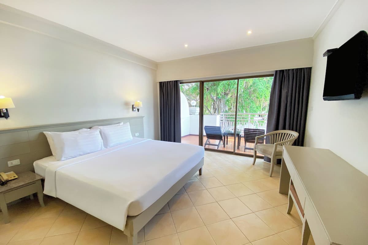 A hotel room with a bed, a desk, a chair, and a TV on the wall.