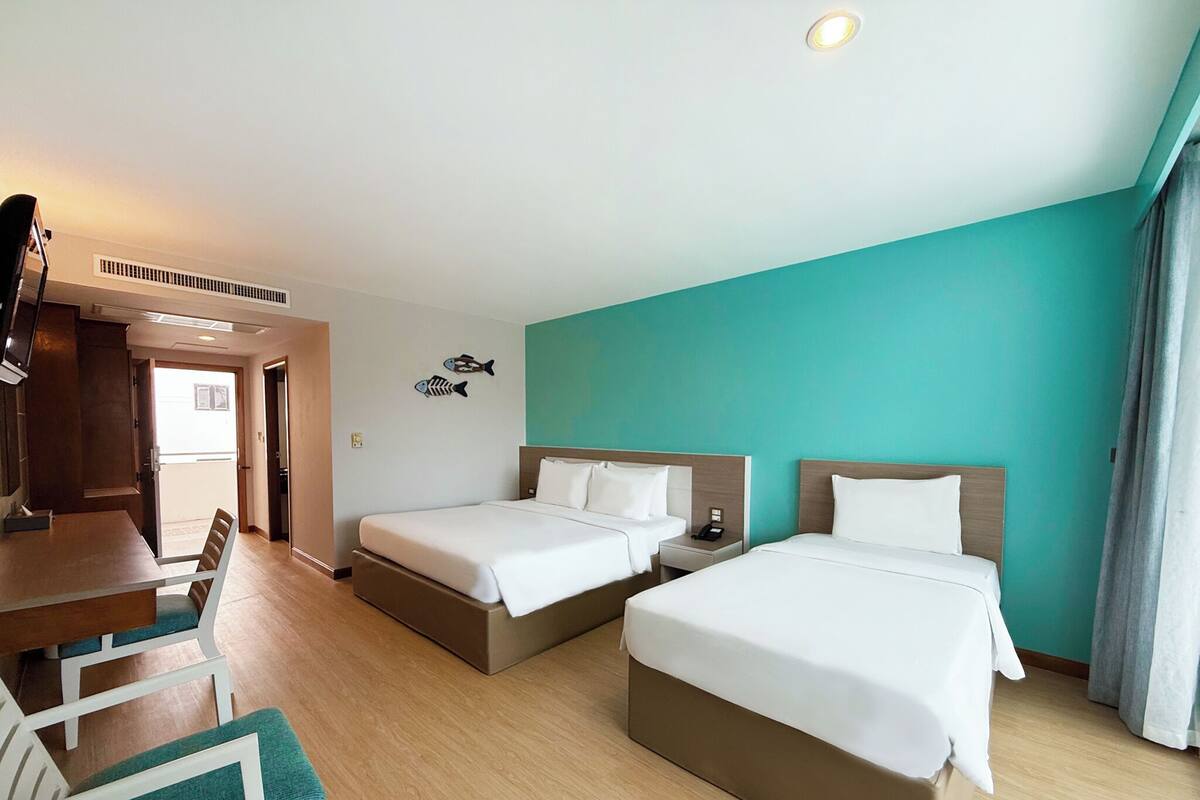 A hotel room with two beds, a desk, and a chair.