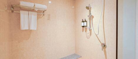 A modern bathroom with a bench, a towel rack, and a shower unit.