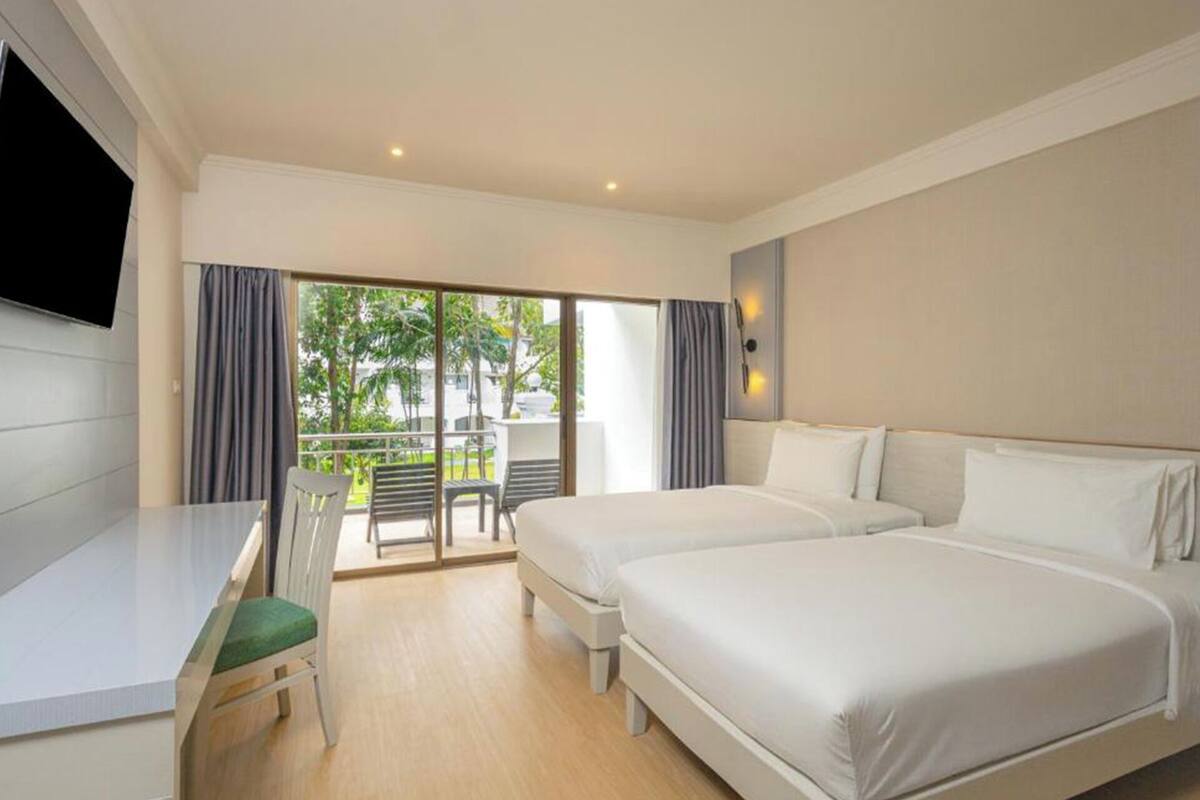 A hotel room with a bed, a desk, a chair, and a TV.