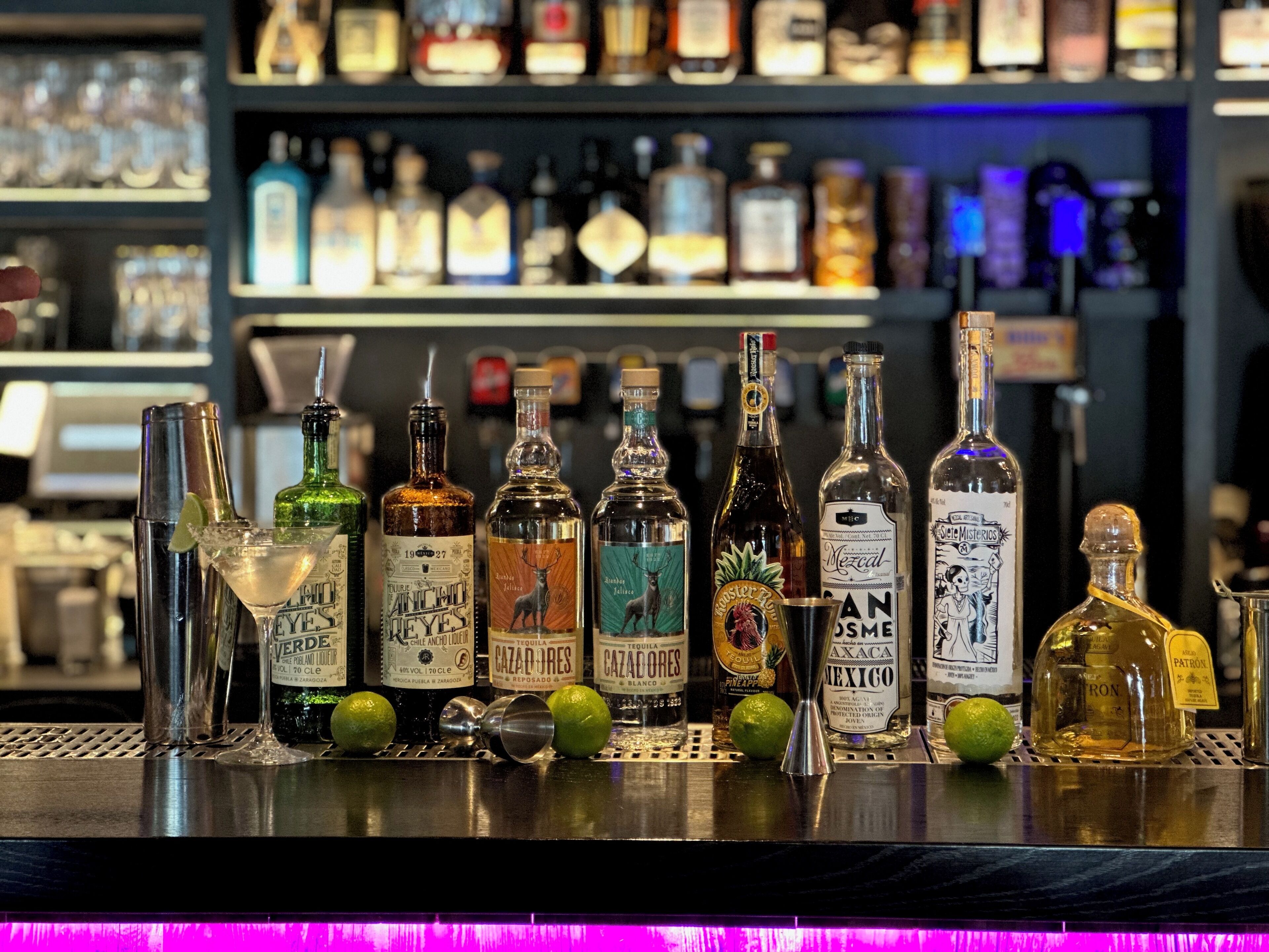 A bar counter with various bottles of liquor and a martini glass.