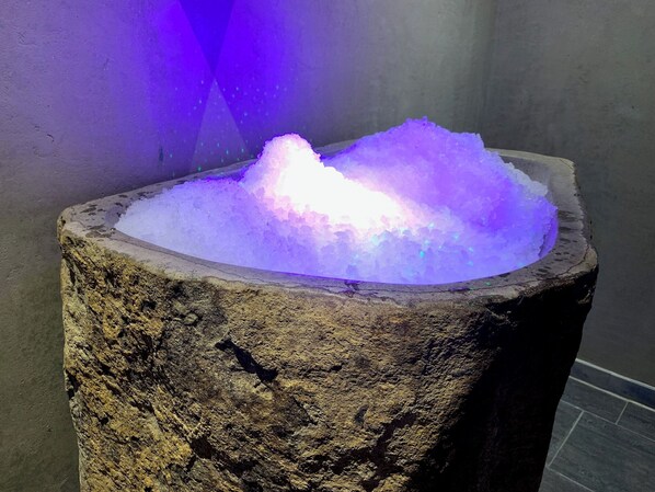 Una cuenca de piedra llena de hielo, iluminada por luces moradas.