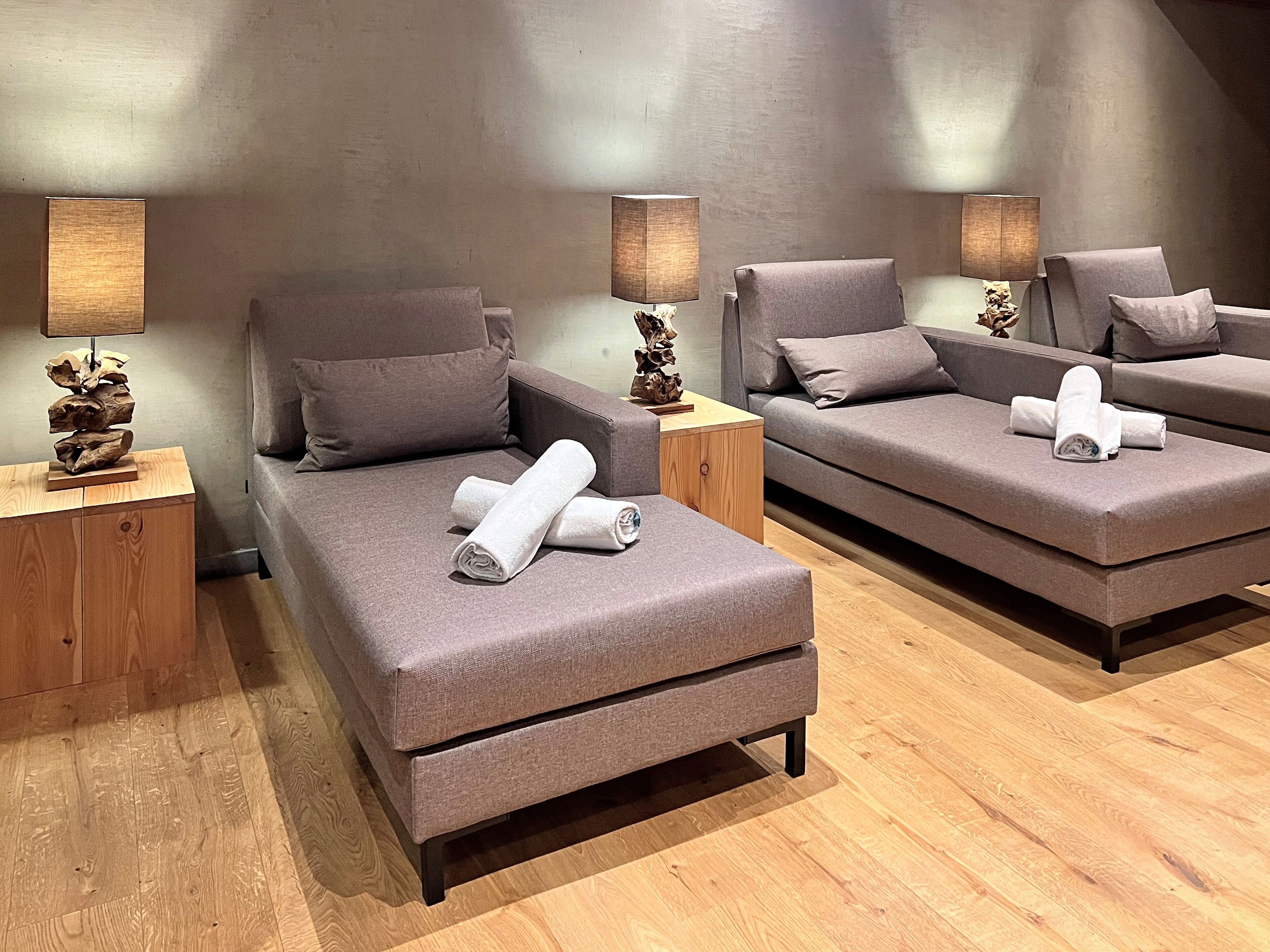 A modern bedroom with two sofas, wooden nightstands, and lamps.
