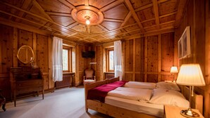 Un dormitorio de cabaña de madera con cama, cómoda, silla y televisor en la pared.