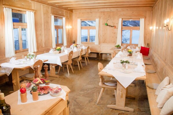 Comedor tipo cabaña de madera con varias mesas dispuestas para comidas, mostrando una variedad de alimentos y bebidas.