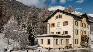 Un hotel con un letrero que indica que es un restaurante, rodeado de árboles y montañas cubiertas de nieve.