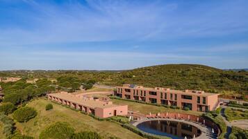 A modern building complex with a central courtyard, surrounded by greenery and hills.