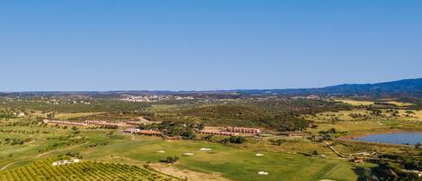A golf course with a clubhouse, a pond, and surrounding greenery.