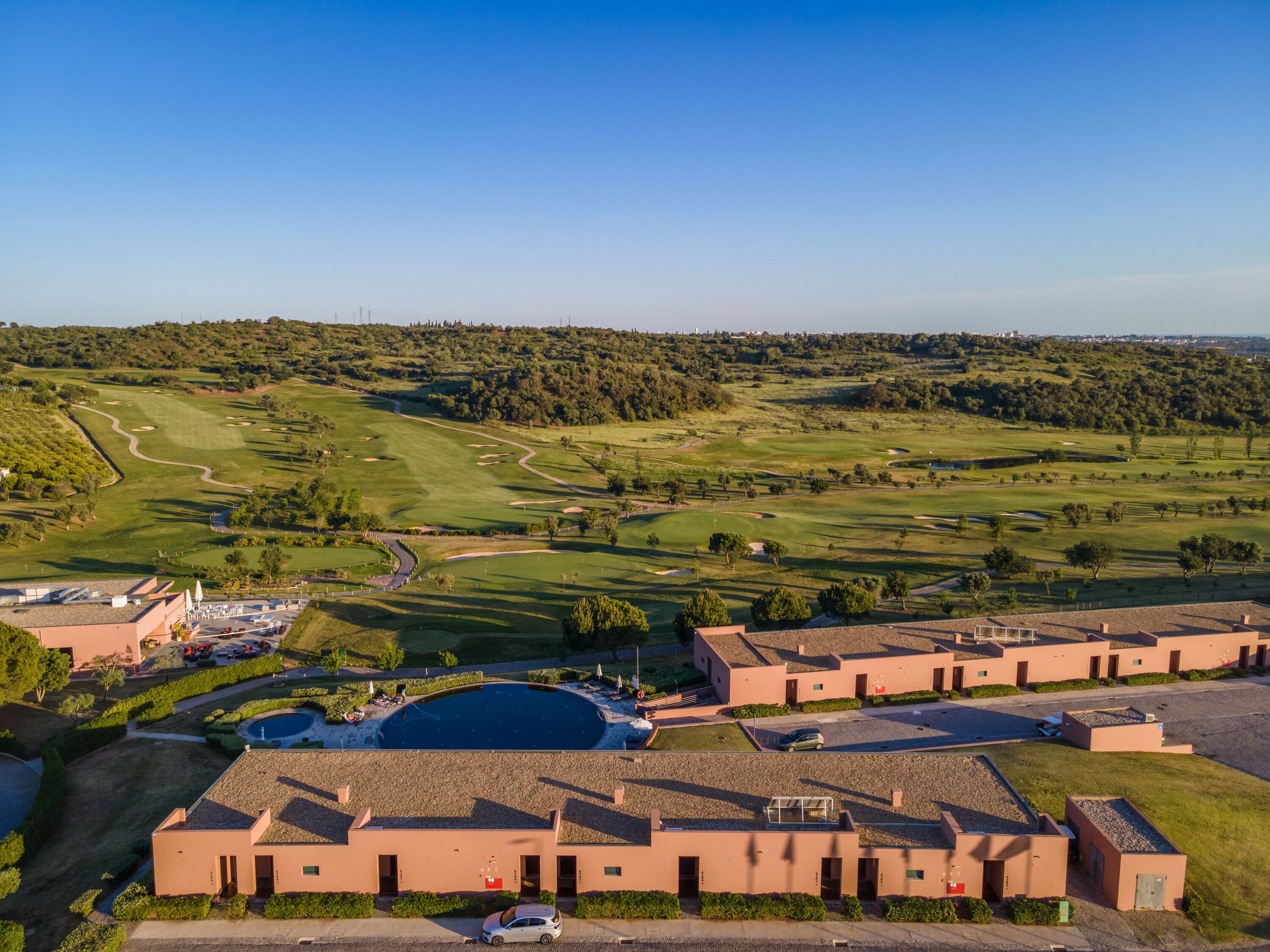 A golf course with a clubhouse and parking area.