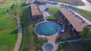 An aerial view of a golf course with a swimming pool, lounge area, and buildings. - NAU Morgado Golf & Country Club (Portimão)
