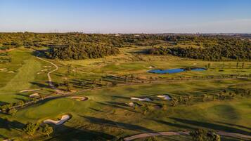 Une vue aérienne d’un parcours de golf comportant de nombreux bunkers, des obstacles d’eau et un fairway bien entretenu.